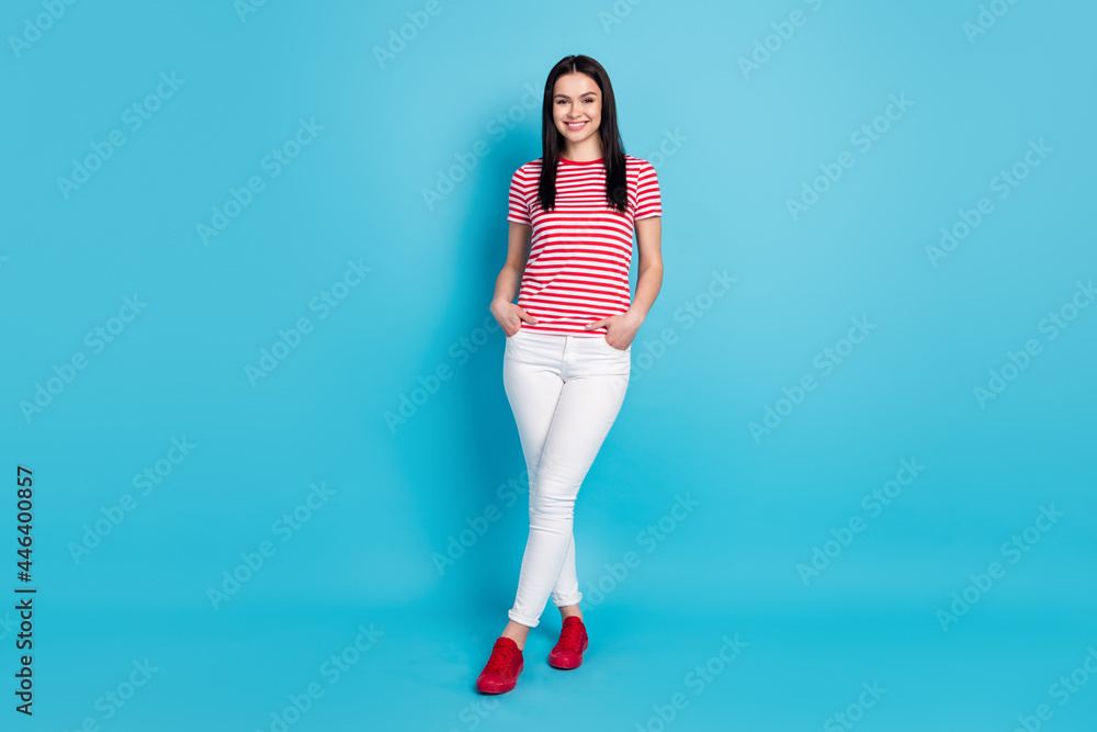Full size photo of young girl happy positive smile confident hands in pocket isolated over blue color background Full size photo of young girl happy positive smile confident hands in pocket isolated over blue color background