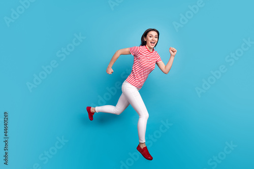 Full size profile side photo of young girl happy positive smile jump go walk run hurry isolated over blue color background