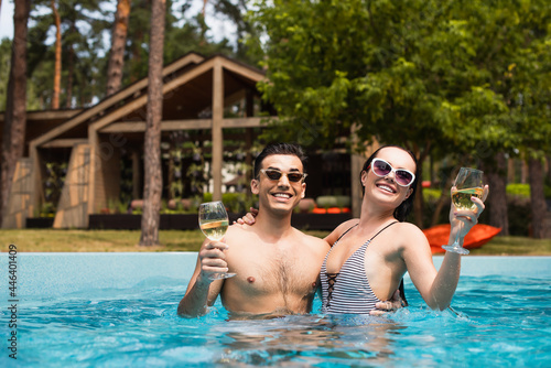 Smiling vacationers relaxing with wine in swimming pool photo