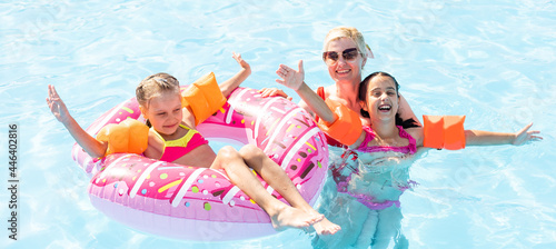 Happy family in the pool, having fun in the water, mother with kids enjoying aqua park, beach resort, summer holidays, vacation concept