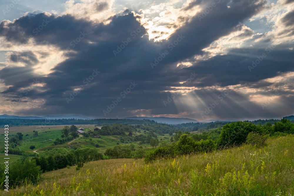 Summer landscape, with dark clouds, and sun rays