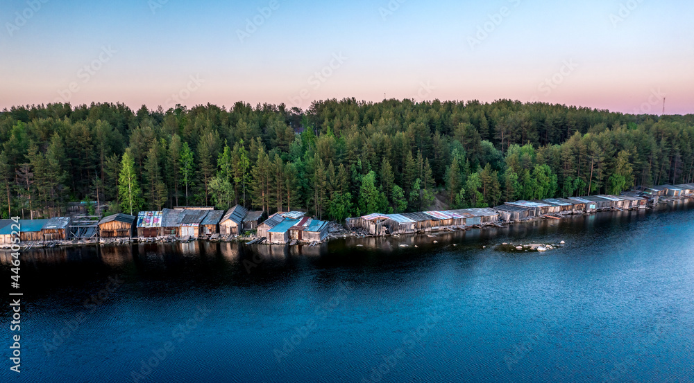 Evening panorama on Karelian lake Kovdozero. Wooden boat garages of fishermen. Settlement Zelenoborsky, Kandalaksha, Murmansk region, Kola Peninsula. Polar day. Karelian landscape