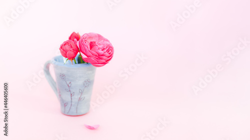 Nice small bouquet of roses in tea cup on pink background with copy space