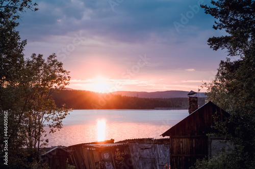 Evening panorama on Karelian lake Kovdozero. Old wooden boat garages on the background of the lake and sunset, Kola Peninsula. Polar sunset. Karelian landscape