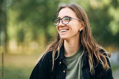 Portrait of a smiling young girl with glasses in the park