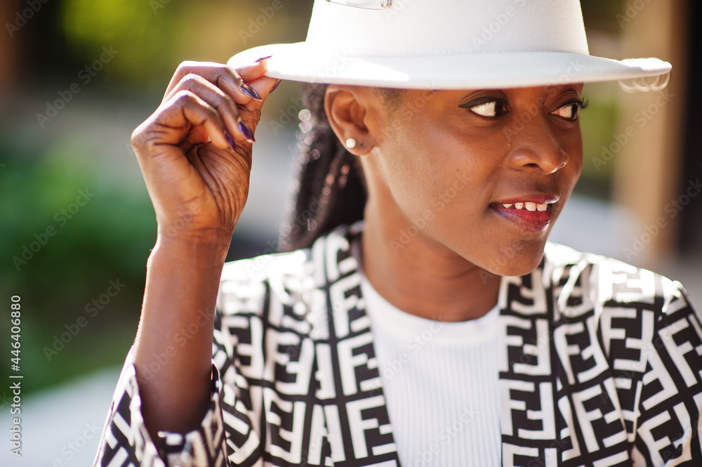 Obraz premium Beautiful african american woman natural makeup wear fashion clothes casual black and white dress code office style total blouse and pants suit and hat.