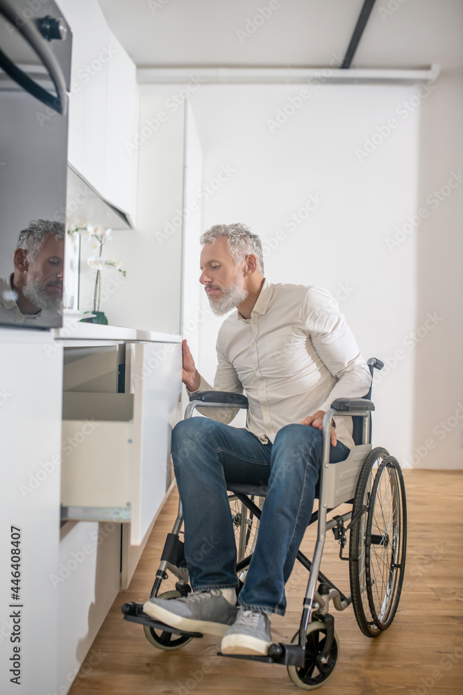 Gray-haired handicapped man in the kitchen getting the breakfast ready Gray-haired handicapped man in the kitchen getting the breakfast ready