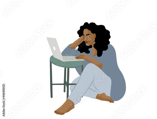 A woman at a small table with a laptop working. 