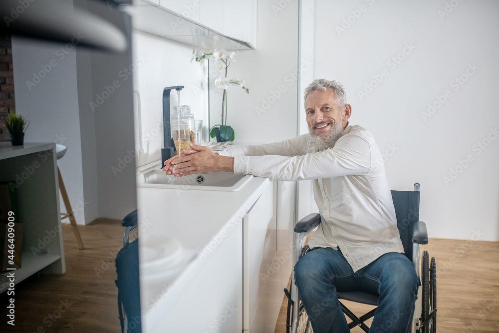 Gray-haired handicapped man in the kitchen getting the breakfast ready Gray-haired handicapped man in the kitchen getting the breakfast ready