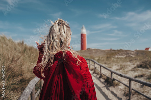 фотографія close-up blonde girl in a red sweater, hair developing in the wind, rear view, o