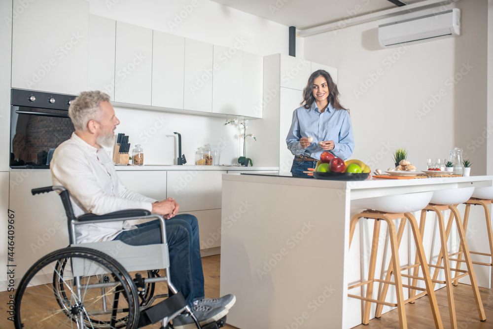Gray-haired handicapped man and his wife at home before breakfast Gray-haired handicapped man and his wife at home before breakfast