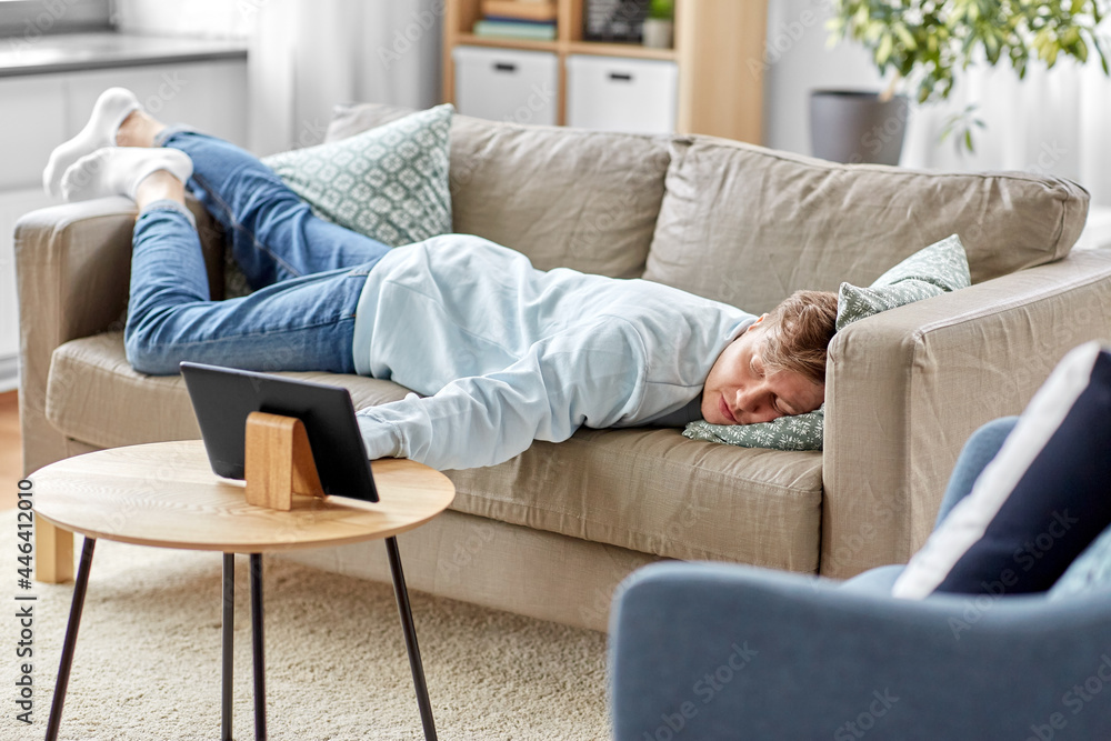 people, boredom and depression concept - bored or lazy young man with tablet pc computer lying on sofa at home people, boredom and depression concept - bored or lazy young man with tablet pc computer lying on sofa at home