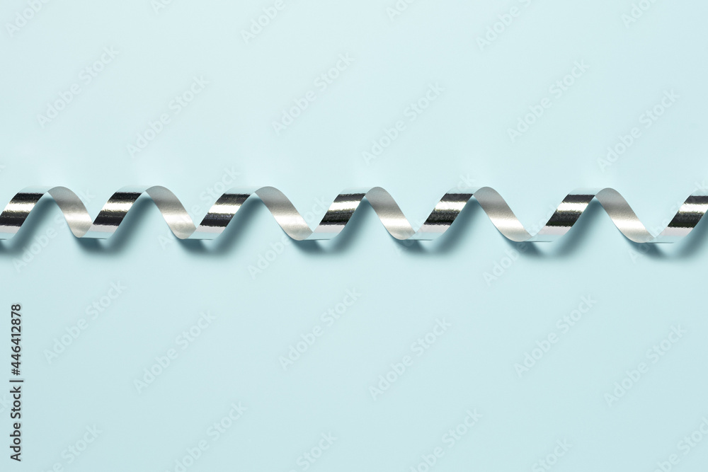 Silver ribbon for wrapping a gift on a plain blue background Silver ribbon for wrapping a gift on a plain blue background