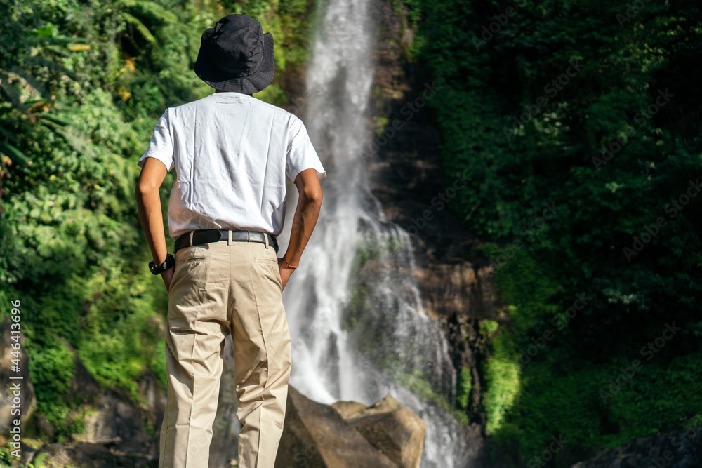 A man enjoying the view of a waterfall A man enjoying the view of a waterfall
