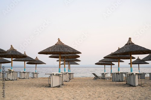 Empty beach loungers with umbrellas waiting for tourists