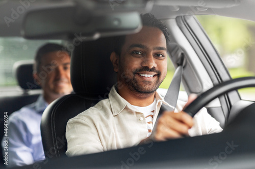 transportation, vehicle and people concept - happy smiling indian male driver driving car with passenger photo