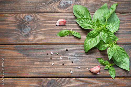 fresh basil, garlic, grains of pink salt and black pepper on a wooden table. Top view