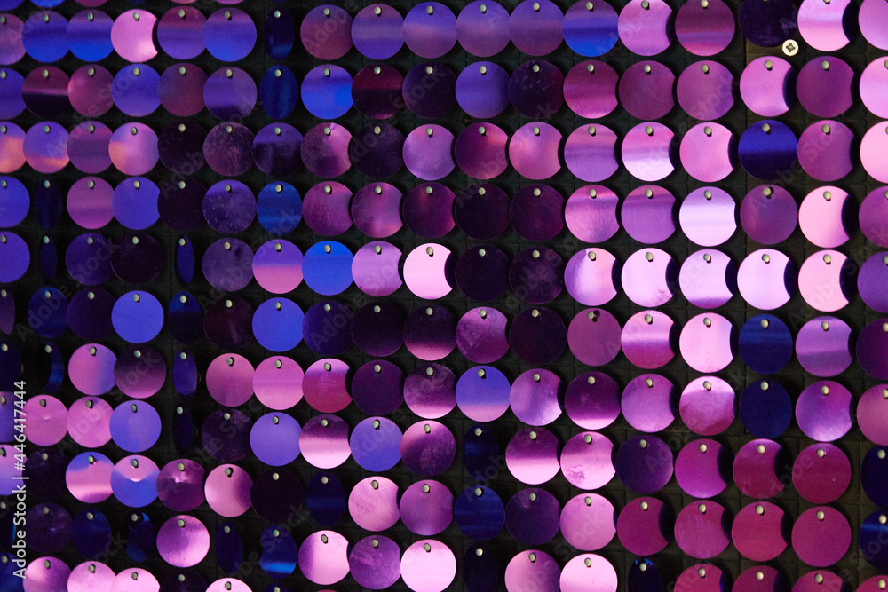 shiny texture of the background, a set of round purple sequins sewn on the fabric like fish scales