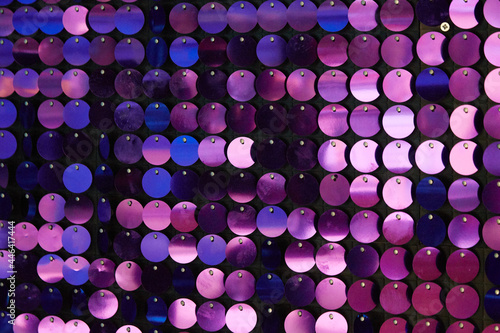 shiny texture of the background, a set of round purple sequins sewn on the fabric like fish scales photo