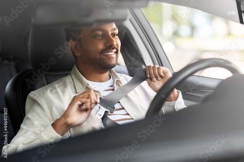 transport, safety and people concept - happy smiling indian man or driver fastening seat belt in car © Syda Productions