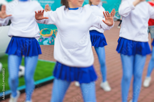 Female group of cheerleader in action, wearing white blue uniform with audience in the background performing and supporting during football game match