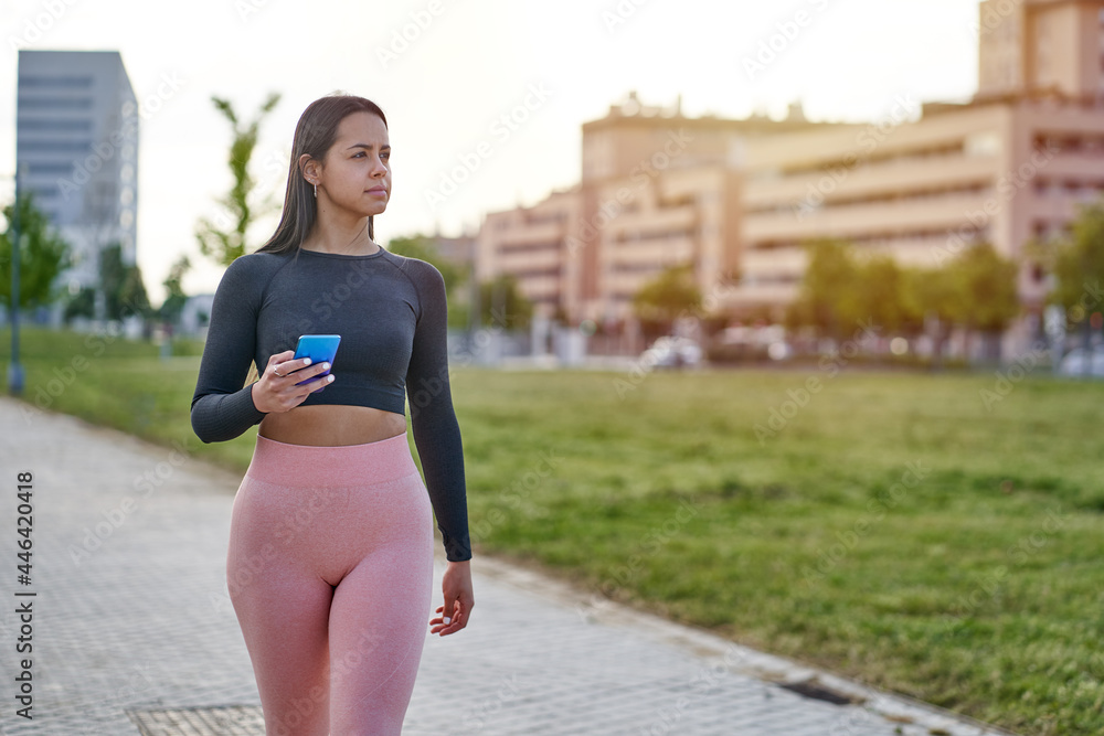 Female model with sportswear and fit body looking at the smart phone
