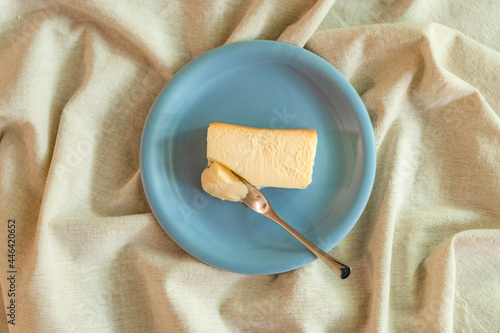 リネンのテーブルクロスに置かれた水色のお皿とベイクドチーズケーキ