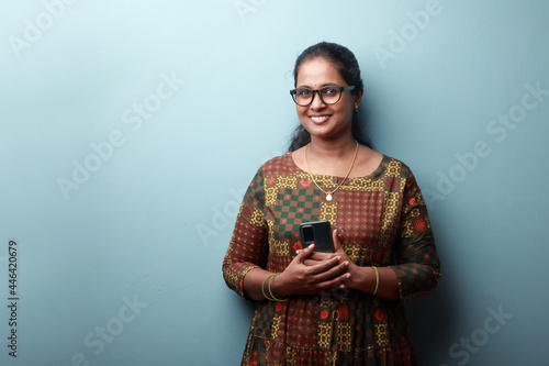 Woman of Indian ethnicity holding a phone with a smiling face expression photo