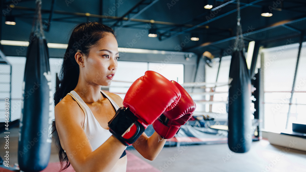 Young Asian lady kickboxing exercise workout punch doing shadow female fighter practice boxing in gym fitness class. Sportswoman recreational activity, functional training, healthy lifestyle concept.