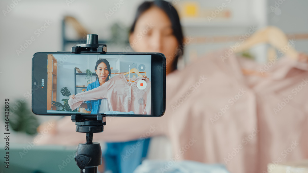 Young Asia lady fashion designer using mobile phone receiving purchase  order and showing clothes recording video live streaming online at shop.  Small business owner, online market delivery concept. Photos | Adobe Stock