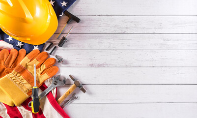 Happy Labor day concept. American flag with different construction tools on white wooden background.
