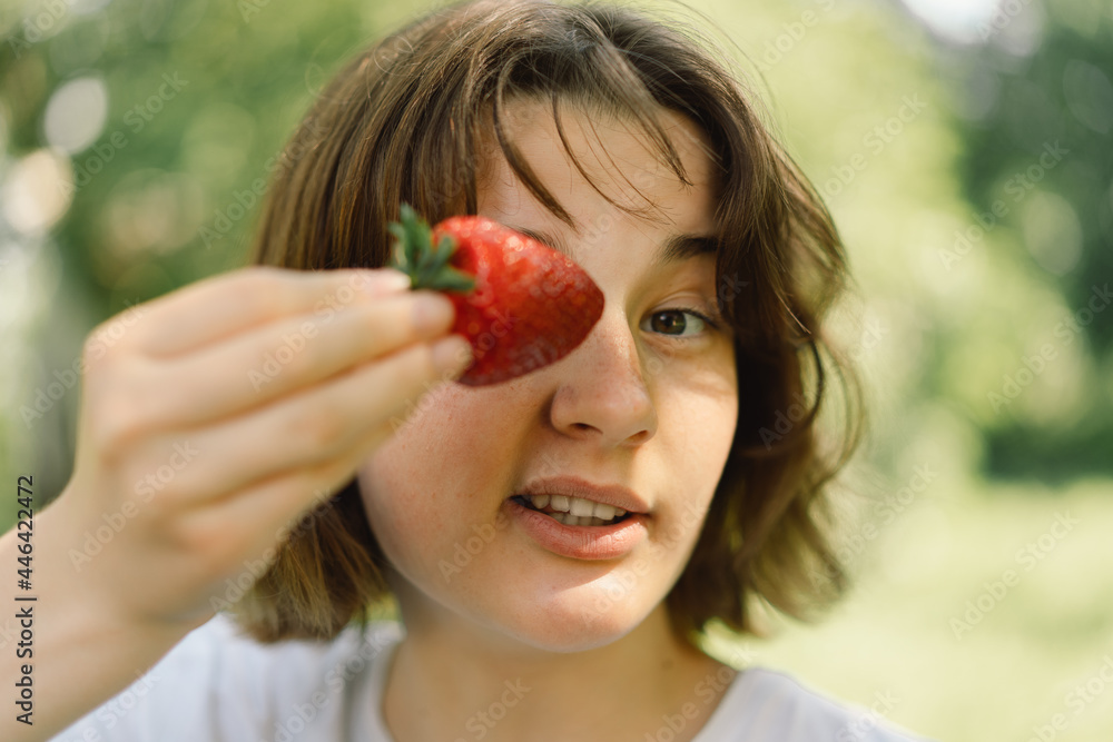 Young Teenager Girl with strawberry in a t-shirt in a outdoor and looking at camera. People and lifestyle concept Young Teenager Girl with strawberry in a t-shirt in a outdoor and looking at camera. People and lifestyle concept