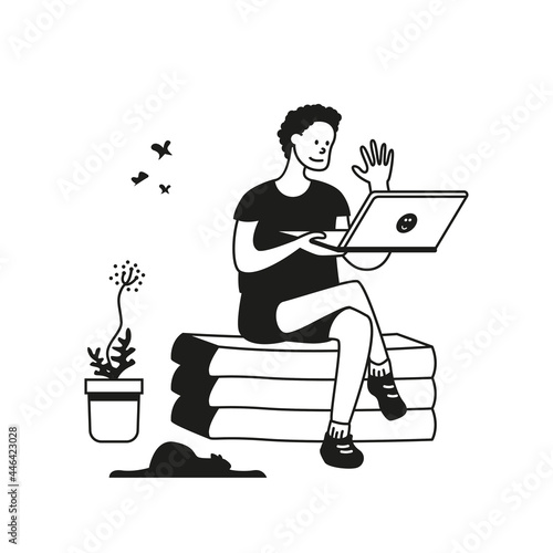 A young man sits on an ottoman with a laptop in his hands and waves his hand to an invisible interlocutor. Communication at a distance using the Internet connection.