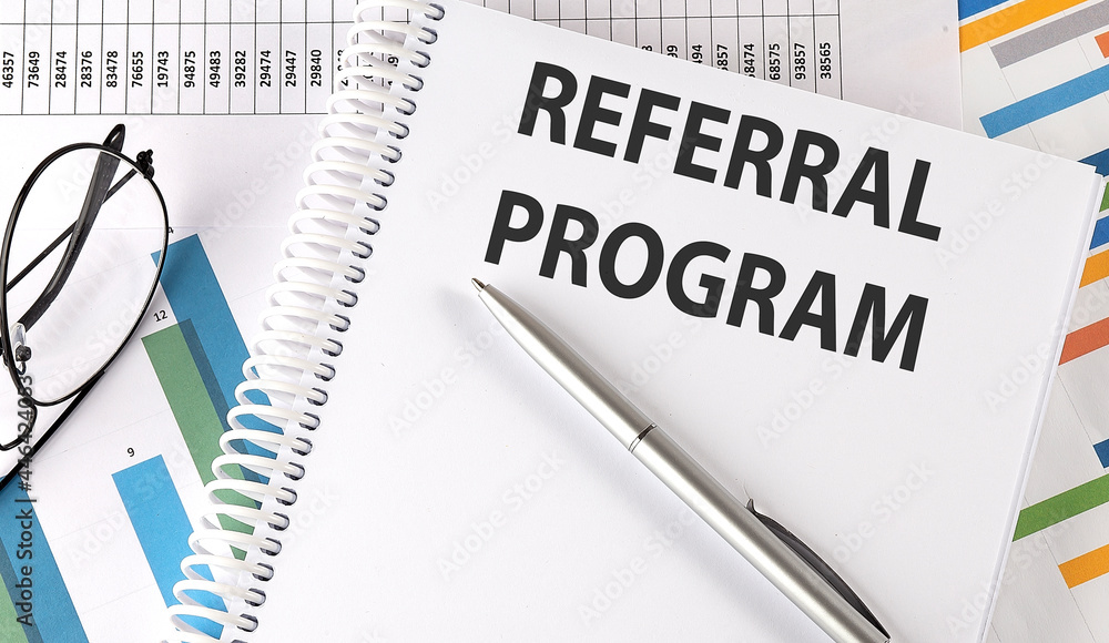 REFERRAL PROGRAM text , pen and glasses on the chart