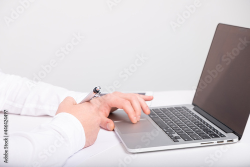 close up of male hands typing on laptop keyboard while working at white desk