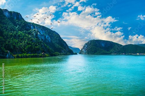 Beautiful landscape on the Danube river. Wooded mountains and blue sky with clouds and birds in flight.