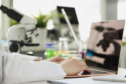 Scientist or student using laptop computer and microscope. online learning
