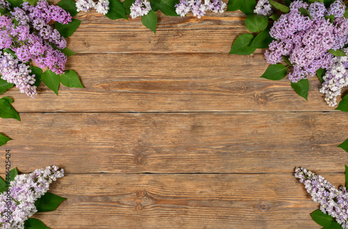 Old dark wooden background with lilac flowers. Copy space