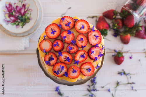 strawberries cut into rounds atop a sponge cake with lemon curd and edible flowers photo