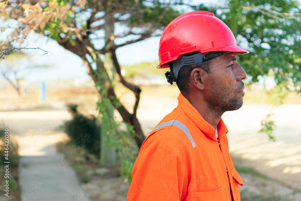 Concept of engineer or technician. Mechanical man in orange uniform looking into the distance Concept of engineer or technician. Mechanical man in orange uniform looking into the distance