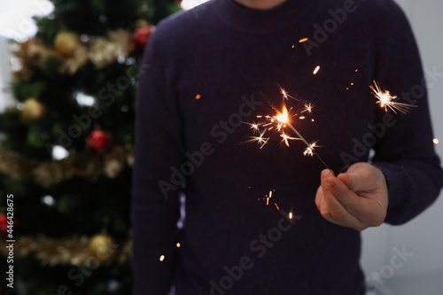 Man holds lighted sparkler in dark closeup photo