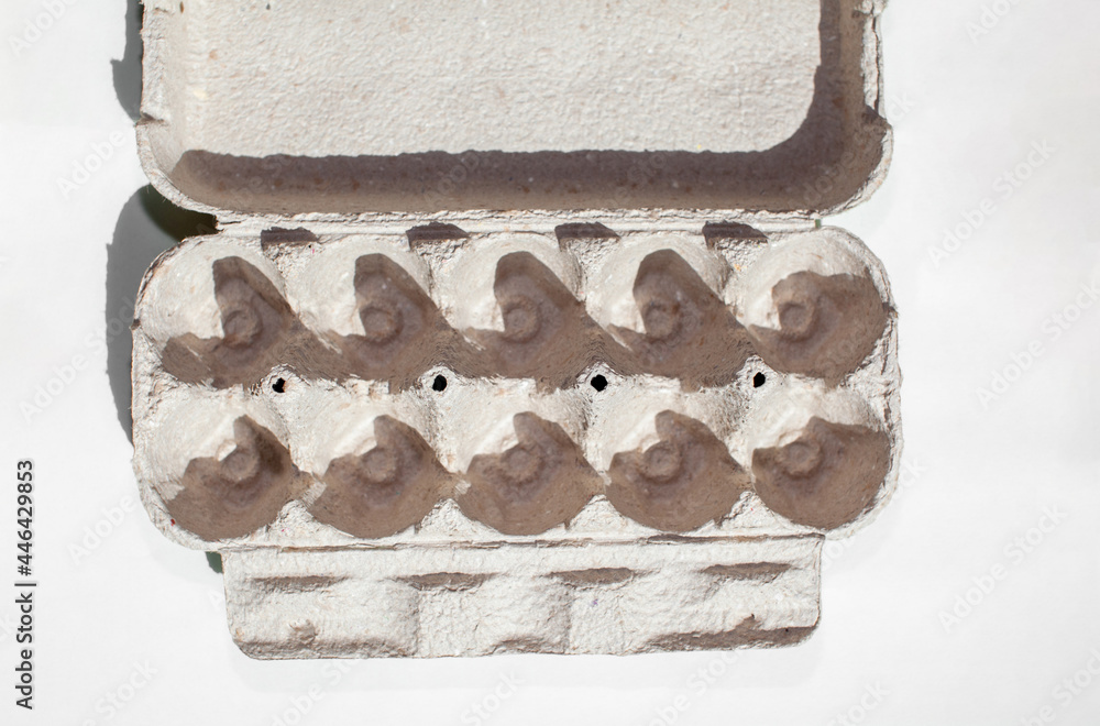 Grey egg carton without eggs on white background. egg carton box made from recycled paper with abstract repeated design pattern Grey egg carton without eggs on white background. egg carton box made from recycled paper with abstract repeated design pattern