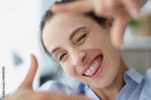 Happy smiling woman makes photo frame with her hands