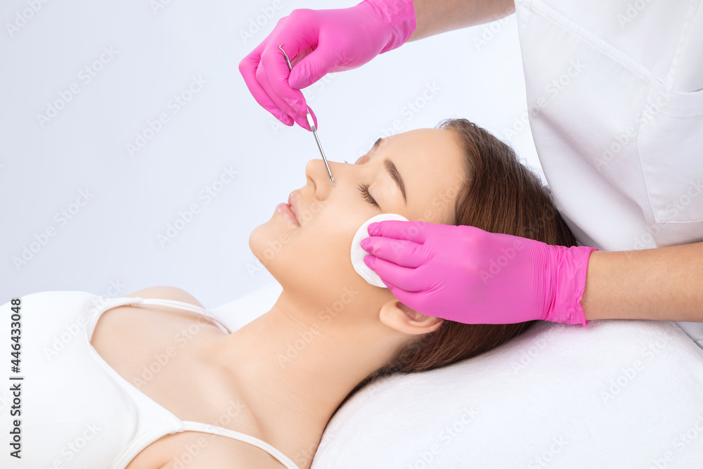 A procedure for cleansing the skin of the face from blackheads and acne. Cosmetologist treats problematic skin of a young woman's face in a beauty salon. Aesthetic cosmetology and makeup concept. A procedure for cleansing the skin of the face from blackheads and acne. Cosmetologist treats problematic skin of a young woman's face in a beauty salon. Aesthetic cosmetology and makeup concept.