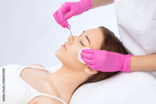 A procedure for cleansing the skin of the face from blackheads and acne. Cosmetologist treats problematic skin of a young woman s face in a beauty salon. Aesthetic cosmetology and makeup concept.
