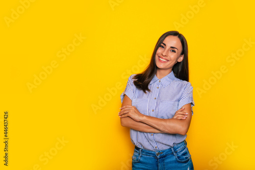 Happy beautiful young confident brunette woman in stylish smart casual wear is posing on yellow background