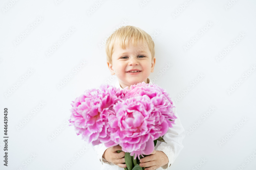child blonde boy with big bouquet of pink peonies on white background. Love and romantic concept