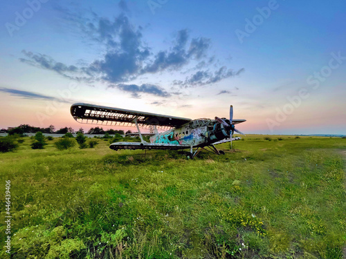 An old and rusty abandoned broken airplane in a green field. 