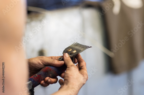 shearer's dirty hands adjusting comb and cutter on handpiece photo