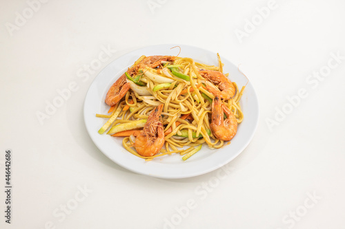 Stir-fried noodles with green peppers, zucchini, carrots and white onions with grilled fried prawns cooked in a Chinese restaurant